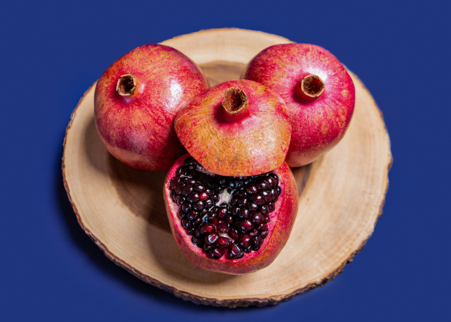 Pomegranate on a wooden plate with a blue background