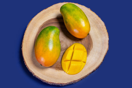 Three East-Indian Mangos on a wooden plate against a blue background