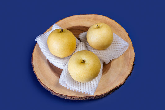 Three Nashi Pear on a wooden plate with a blue background